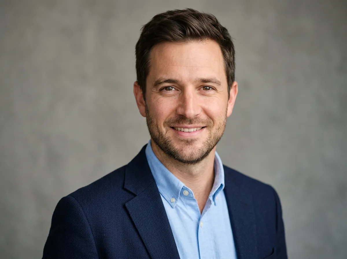 Professional headshot of a man in his 30s named Daniel L, casual smart attire, neutral grey background, friendly look